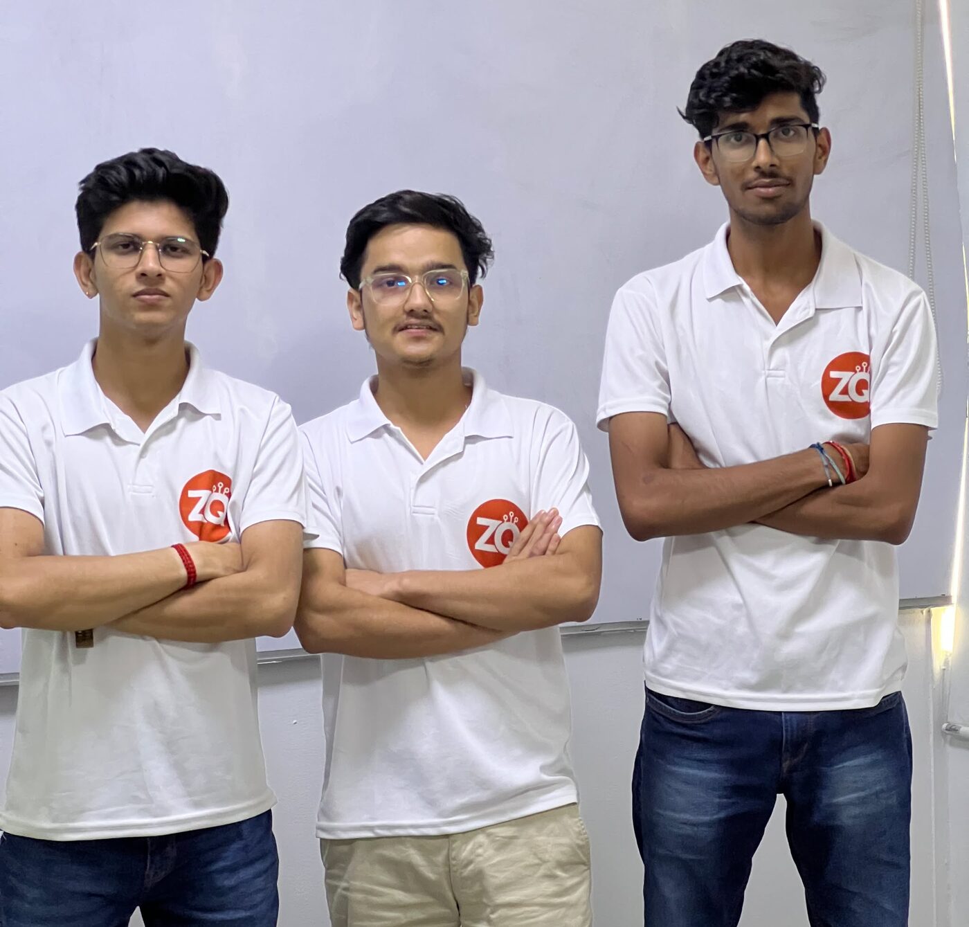 The three Zobique co-founders standing in front of a whiteboard, wearing white polo shirts with the Zobique logo